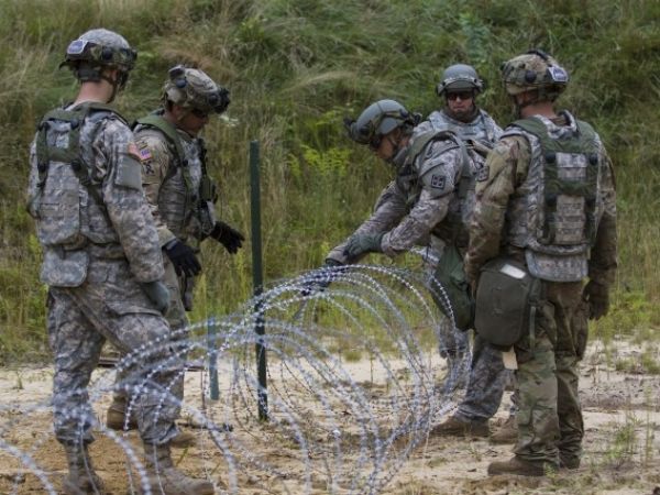 Les soldats déploient des concertinas à ruban barbelé comme barrières d'entraînement militaire.