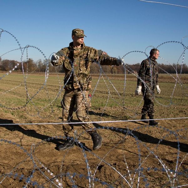 4 soldiers are installing BTC NATO-22 barbed tape along the border line.