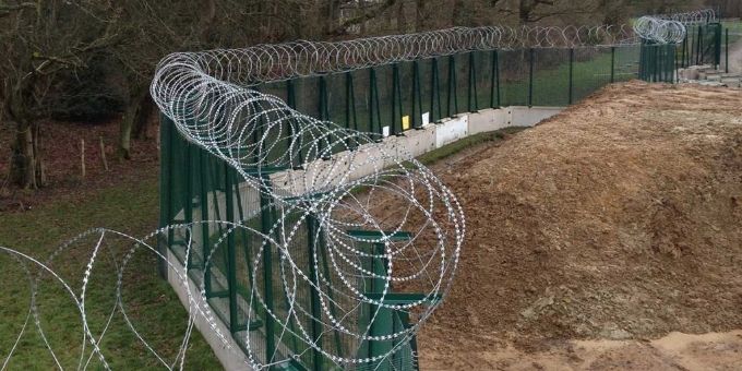 Des fils de rasoir sont installés sur le dessus de la clôture de sécurité le long du chantier.