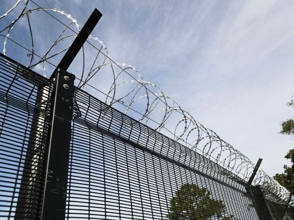 Cross razor wires are installed at the top of curvy weld fence.