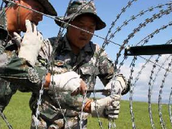 Los soldados llevan guantes para la instalación de alambre de púas.